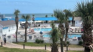 A pool area with multiple pools, palm trees, and a view of the ocean.
