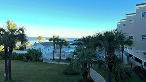 A hotel with a pool area, palm trees, and a view of the ocean.