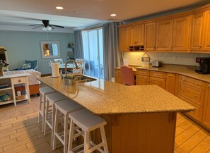 A kitchen with a granite countertop, wooden cabinets, and a bar stool seating area.