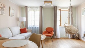 A modern living room with a sofa, armchair, round table, and a hanging chair. - Marllon Suites – Casa Rheinblick Apartments – Bella Suite (Basel)