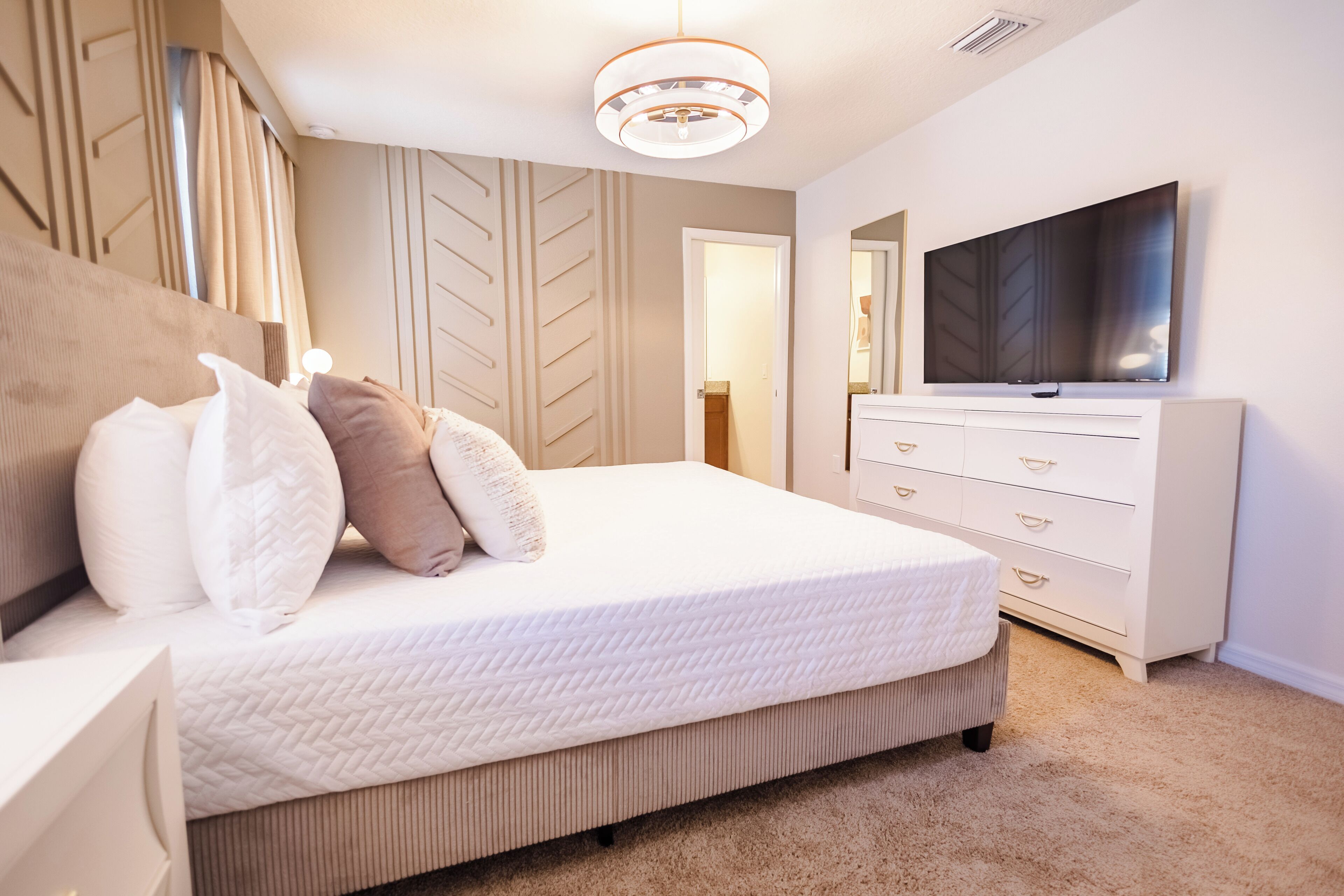 Une chambre à coucher moderne avec un grand lit, une télévision et une commode.