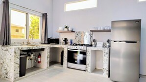 Una cocina moderna con encimeras de mármol, estufa a gas, horno y refrigerador de acero inoxidable.