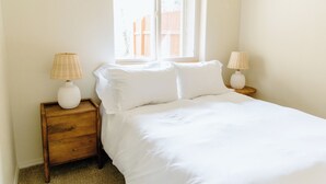 A bedroom with a bed, two nightstands, two lamps, and a window with a view of a wooden fence. - Spacious 5-bedroom townhome in Moscow (Moscow)