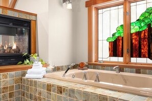 A bathroom with a stone-tiled sink, a glass shower enclosure, and a fireplace. - Bainbridge Is waterfront lodge w private beach access and extensive amenities (Bainbridge Island)
