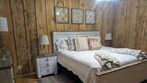 A bedroom with a wooden headboard, a white bedspread, and decorative wall art.