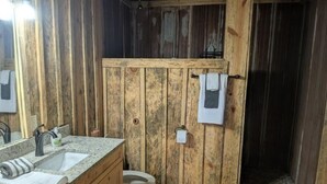 A rustic bathroom with wooden walls, a sink, and a toilet.