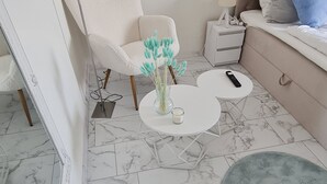 A modern living room with a white sofa, a round coffee table, and a blue rug. - DEICHLIEBE 1 - fantastic view, own garage & contactless check-in (Bremerhaven)