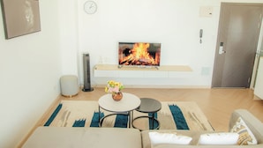 A modern living room with a flat-screen TV, a fireplace, a sofa, a coffee table, and a clock on the wall. - 1 bedroom spacious, modern and cozy apartment nestled in upperhill nairobi Kenya (Nairobi)