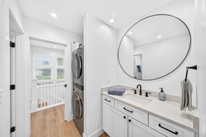 Un baño moderno con un espejo grande, un lavabo y una zona de ducha.