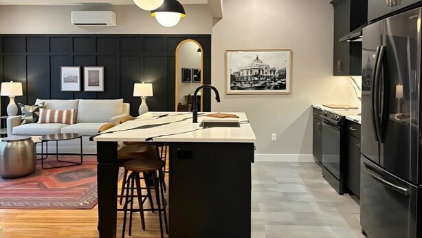 A modern kitchen with a central island, black cabinets, and stainless steel appliances. - Wander & Wonder: A Hidden Gem in Portland’s Heart (Portland)
