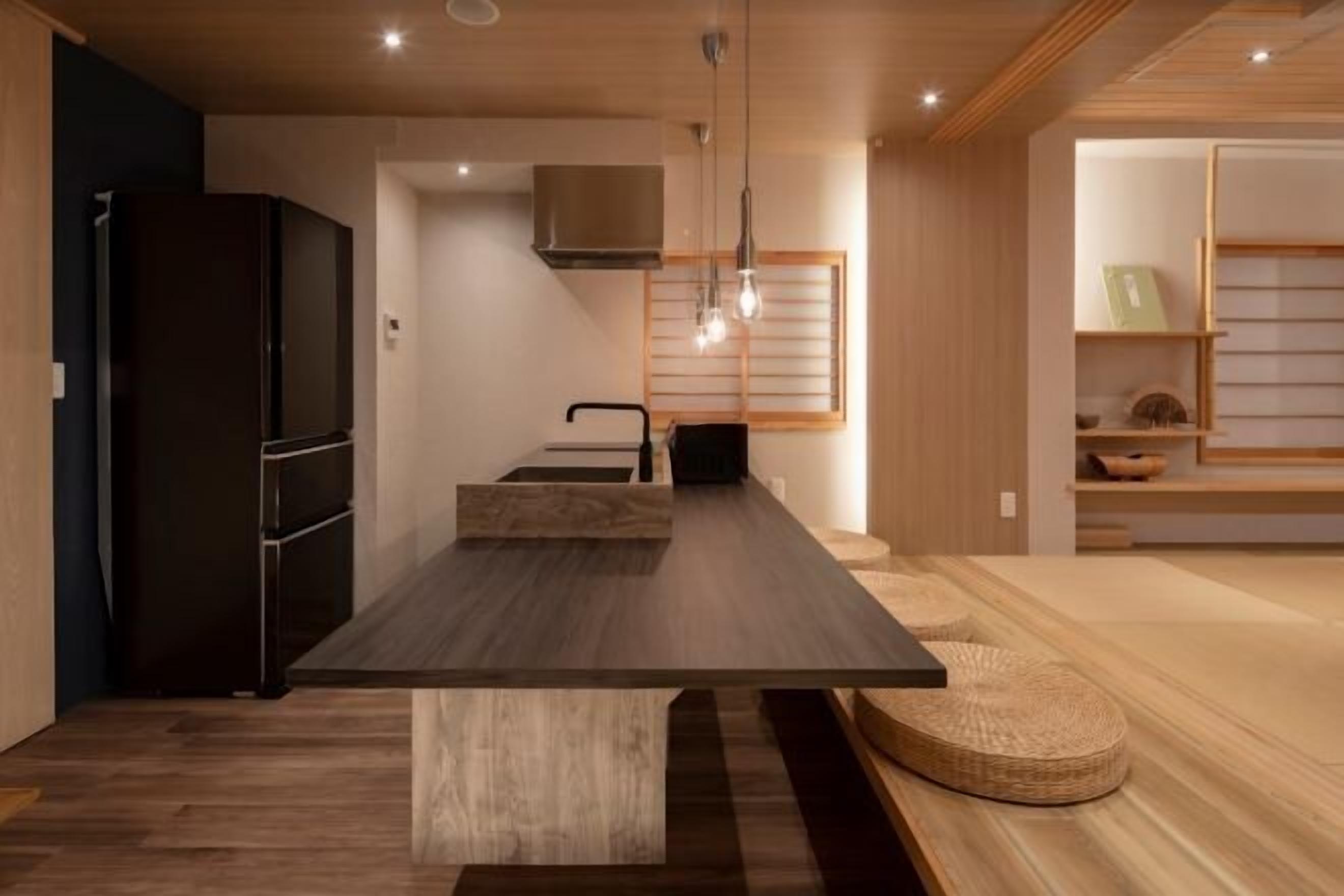 Una cocina moderna con una mesa de madera oscura, electrodomésticos integrados y un diseño minimalista.