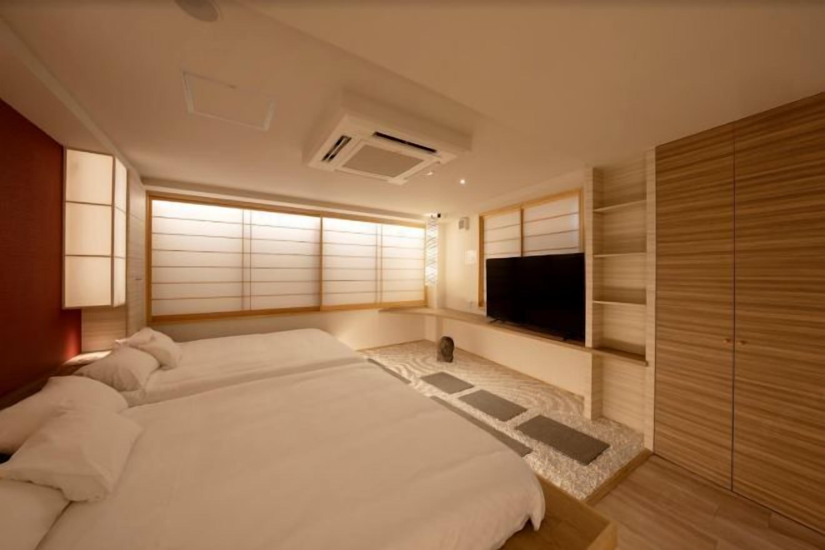 A hotel room with two beds, a TV, and a sliding wooden wardrobe.