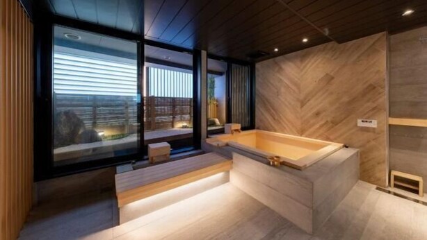 Un baño moderno con una bañera de madera, un ventanal grande y un revestimiento de pared con patrón de espiga.