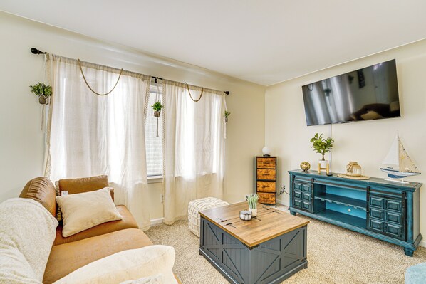Een woonkamer met een bank, salontafel en een blauwe kast met decoratieve objecten.