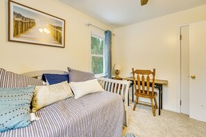 Een slaapkamer met een bed, kussens, een stoel, een raam en een deur.