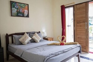 A bedroom with a bed, pillows, a nightstand, a lamp, a painting, and a sliding door. - Pondok Kana and Hostel by Ecommerceloka (Bali)