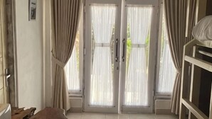Una habitación con puerta de vidrio corrediza, una cama litera y una pequeña mesa.