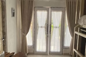 A room with a sliding glass door, a bunk bed, and a small table. - Pondok Kana and Hostel by Ecommerceloka (Bali)