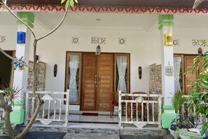 A house with a porch, two wooden doors, and a small garden area. - Pondok Kana and Hostel by Ecommerceloka (Bali)