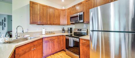 A modern kitchen with wooden cabinets, stainless steel appliances, and a granite countertop.