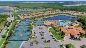 An aerial view of a resort with multiple tennis courts, a swimming pool, and a parking lot. - Estate Bungalow With TPC golf course. Luxury, in and out. (Naples)