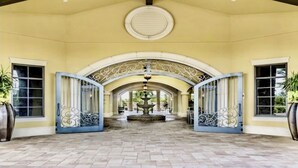 A covered entrance with arched doorways, a central fountain, and potted plants. - Estate Bungalow With TPC golf course. Luxury, in and out. (Naples)