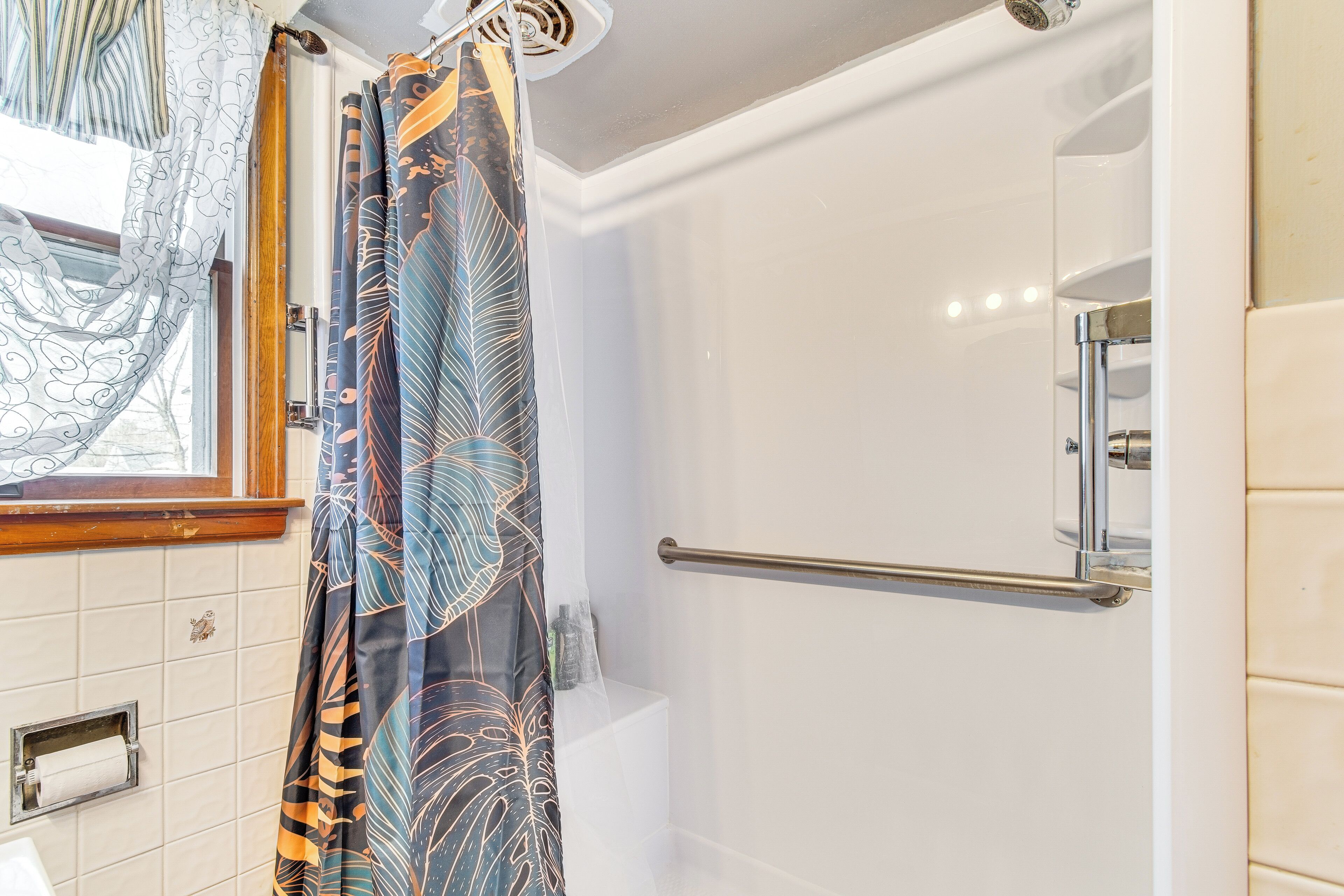 A modern bathroom with a shower, a towel rack, and a toilet.