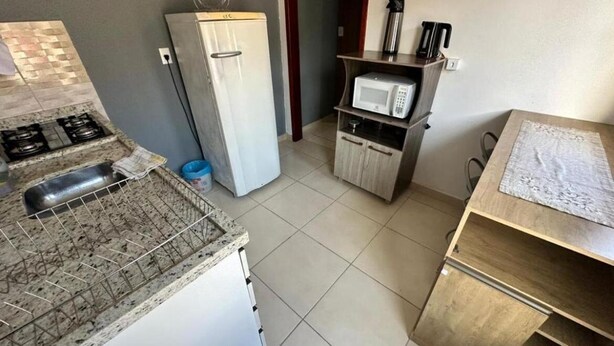Una cocina compacta con estufa a gas, refrigerador, microondas y un mueble de madera.