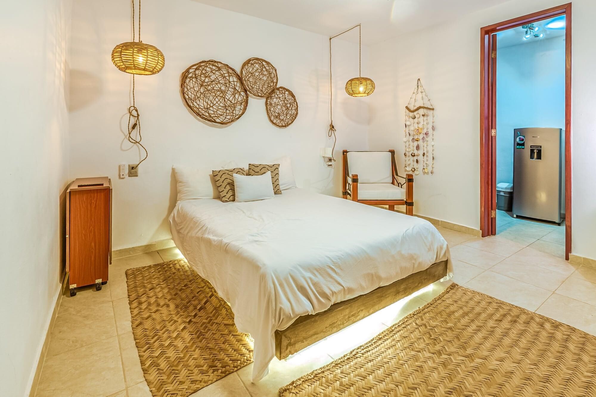Une chambre à coucher avec un lit, une chaise et une petite table. Les murs sont décorés et il y a un luminaire suspendu au plafond.