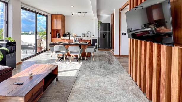 Une cuisine moderne dotée d’un grand téléviseur, de meubles en bois et d’un coin repas avec un sol en marbre.