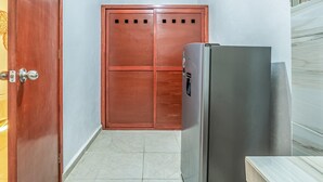 Passadís estret amb una porta de fusta i un frigorífic d'acer inoxidable.