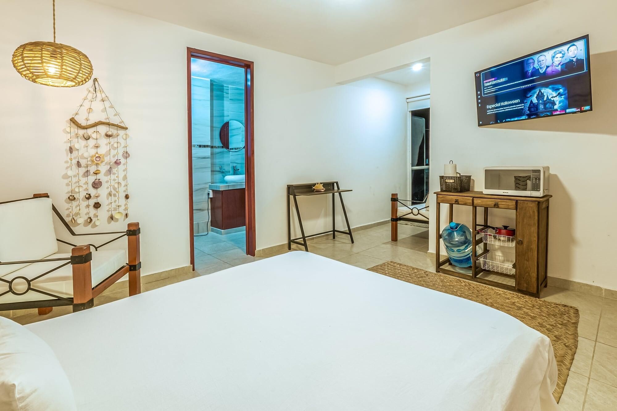 Een hotelkamer met een bed, een televisie, een klein tafeltje met een magnetron en een waterdispenser.