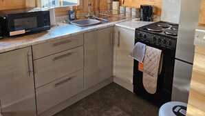 Una cocina compacta con microondas, estufa, fregadero y refrigerador.