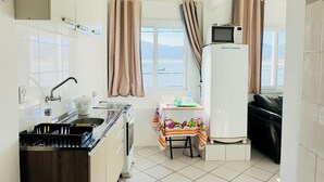 Cuina compacta amb rentamics, fogó i nevera. Una finestra amb cortines ofereix vista a l'exterior.