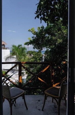 Enjoy the serene ocean views from this balcony surrounded by lush greenery and a majestic tree.