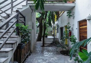 Stroll through this serene, enclosed courtyard surrounded by lush greenery and a staircase leading to an upper level.