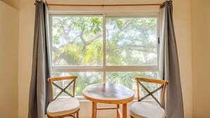 Ein Zimmer mit großem Fenster, zwei Holzstühlen und einem kleinen runden Tisch.