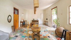 Ein Zimmer mit Schachbrettboden, Holzmöbeln, einer hängenden Pflanzkorb und einer Tür zu einem weiteren Raum.