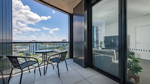 A balcony with a table and chairs, a view of a cityscape, and a door to the right.