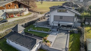 Ein modernes Haus mit großer Garage, überdachter Terrasse und gepflegtem Rasen.