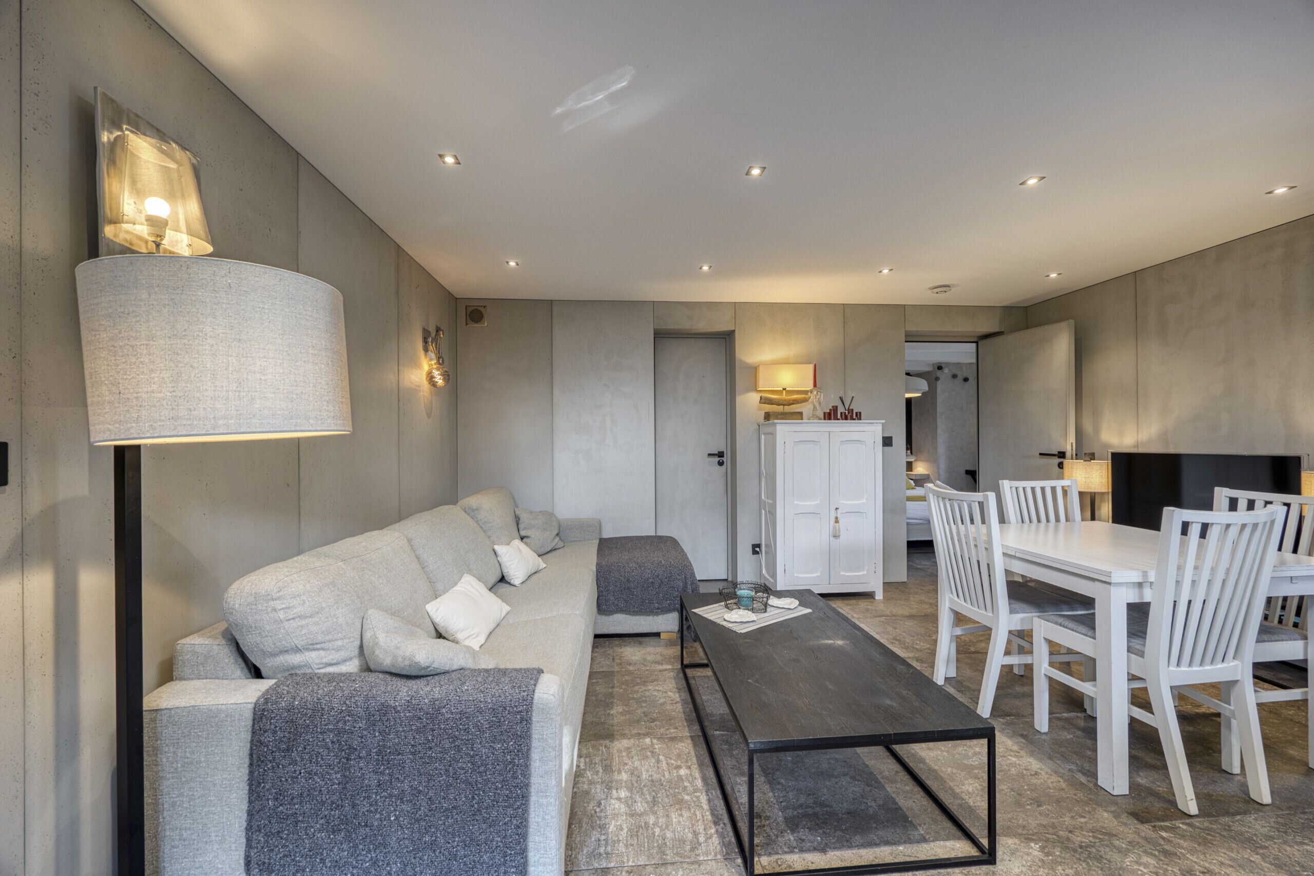 Un salon moderne comprenant un canapé, une table basse et un coin repas avec des chaises et une table.