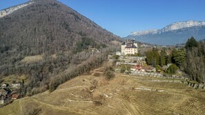 Ein schlossartiges Gebäude, umgeben von einer gebirgigen Landschaft.