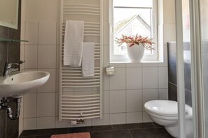A bathroom with a white sink, a towel rack, a toilet, and a window with a vase of flowers. - Haus Postwiese - 118 m² vacation home, only 150 m from the ski lift (Winterberg)