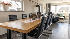 Uma área de refeições moderna com mesa de madeira, cadeiras pretas e um centro de mesa decorativo.