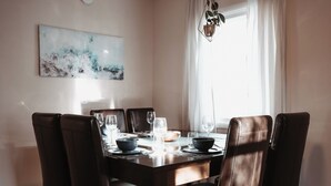 Een eetruimte met een houten tafel, zes lederen stoelen en een moderne hanglamp.