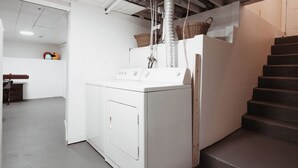 Een praktische wasruimte met een wasmachine, een droger en een trap naar een hoger gelegen verdieping.