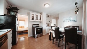 Een moderne keuken met een eethoek, houten vloeren en uitzicht op de woonkamer.