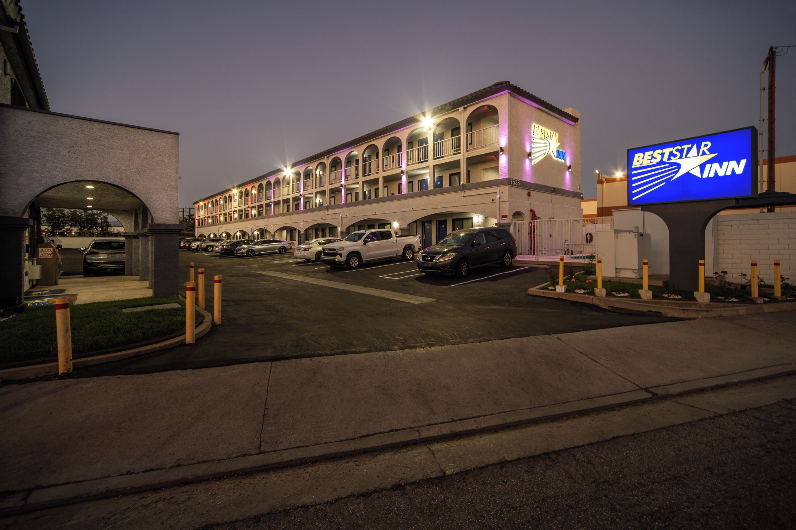 A multi-story hotel with a central courtyard, a parking lot, and a visible sign for BestStar Inn.