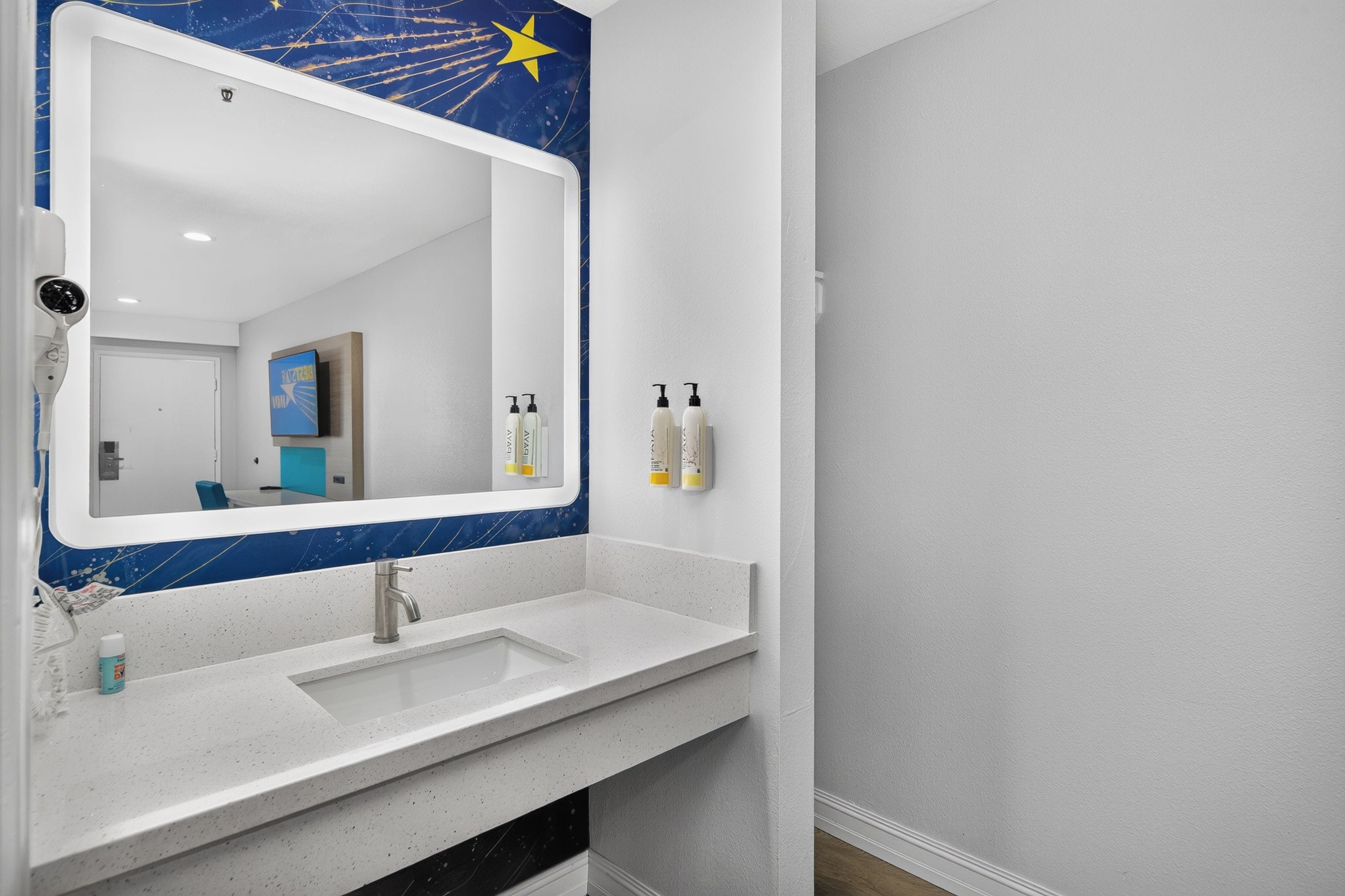 A bathroom with a white sink, a mirror with a star design, and toiletries on the wall.