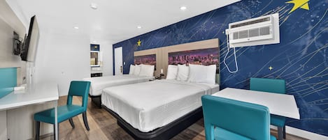 A hotel room with a bed, two chairs, a desk, and a wall with a starry night design.